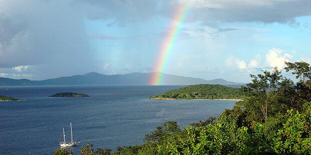 A view of the Caribbean with forest-covered islands with white sand beaches and a rainbow in the distance