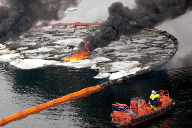 A floating boom contains an area of sea ice and burning oil 