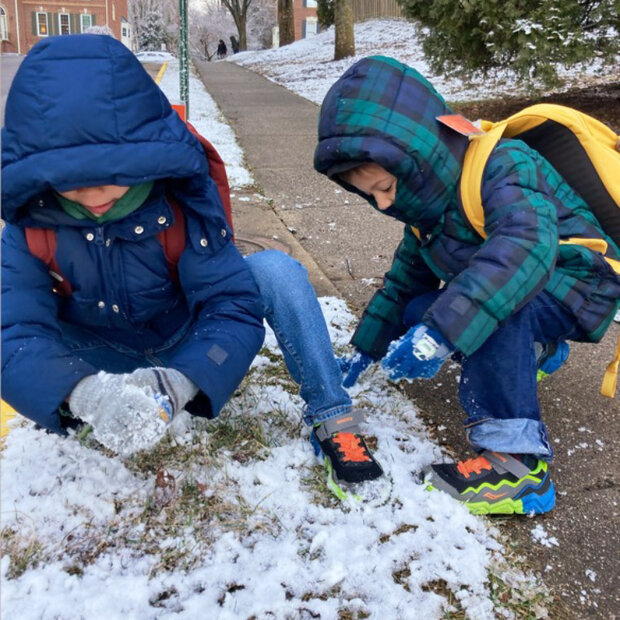 Two kids scraping thin snow into snowballs