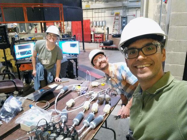 people in hardhats standing around a table on which air sampling equipment are laid out