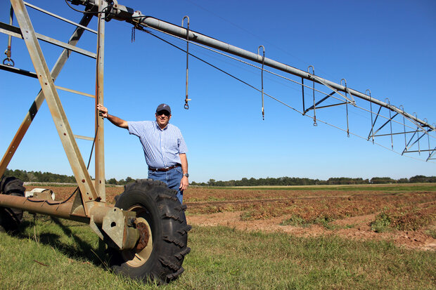 Ron Bartel standing in a field next to a large irrigator