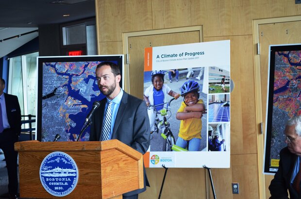 Brian Swett at a podium with posters in background