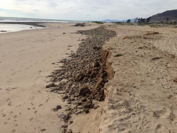 A long stretch of river rocks make a berm along the seaward wide of a bike path