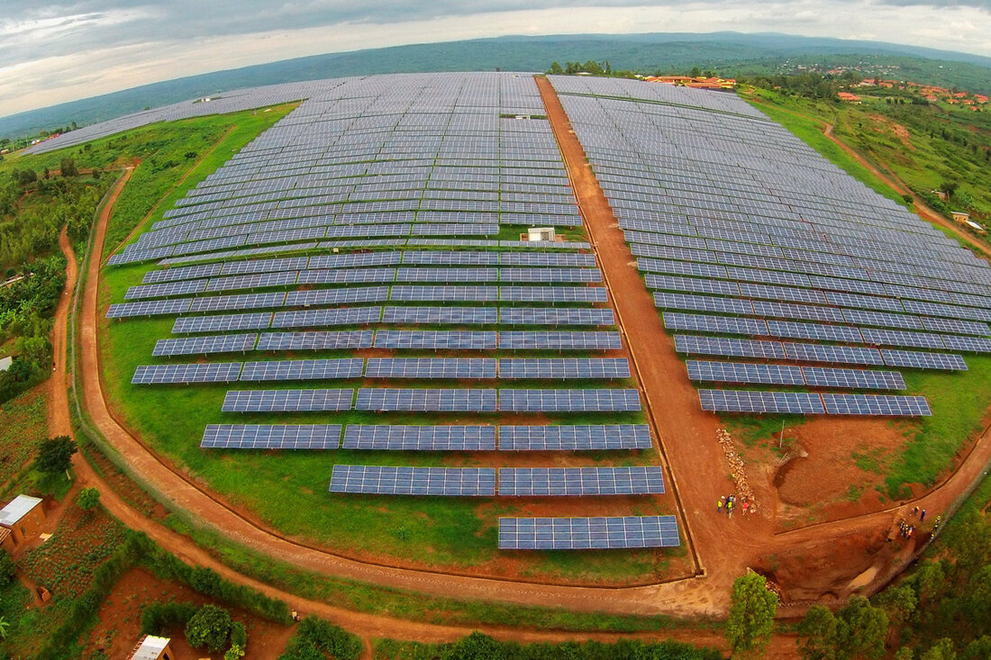 Aerial photo of a solar array surrounded by pockets of trees and red dirt roads