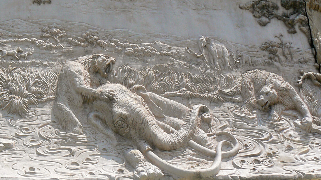 A carved mural of a saber-tooth cat attacking a mammoth trapped in the La Brea tar pit