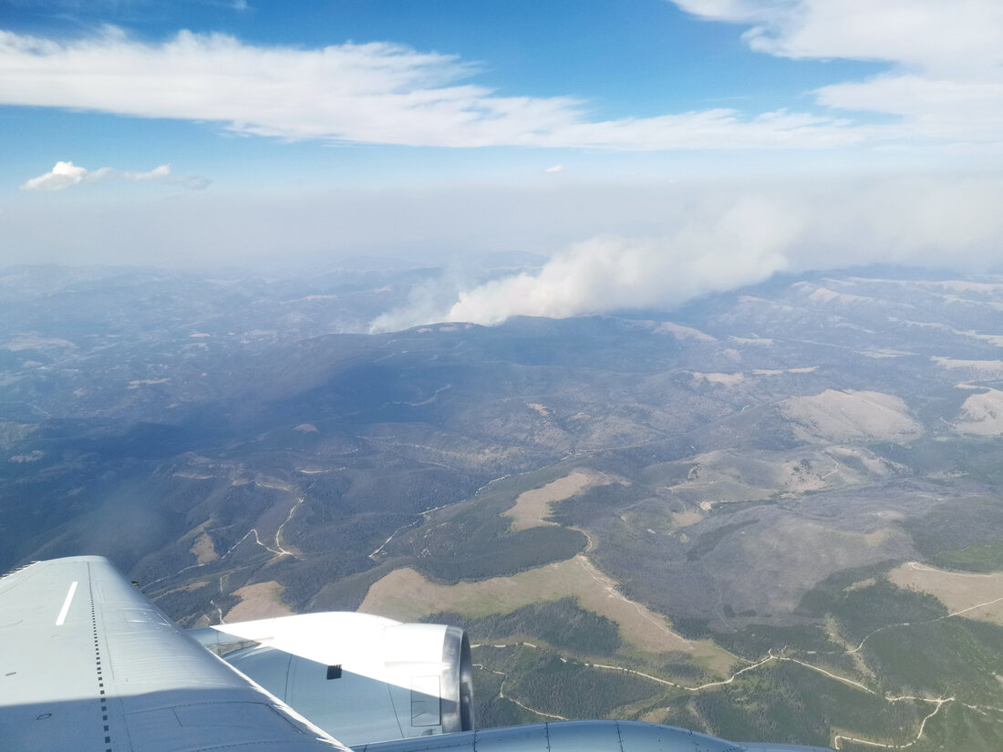 View from an airplane window of a plume of wildfire smoke