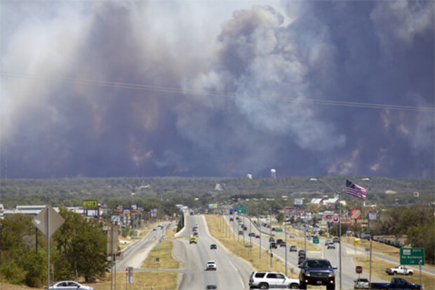 A wall of smoke towers in the background of this September 5, 2011, photo of a stretch of Highway 71 in Bastrop County, Texas
