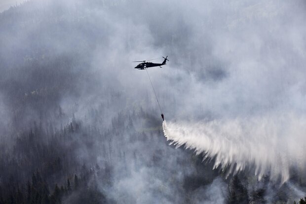 Helicopter dropping water on a smoky forest fire