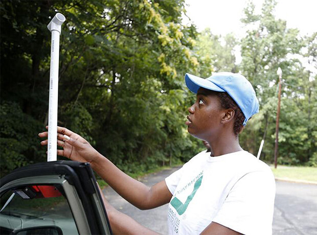 A woman positions a temperature sensor on a car