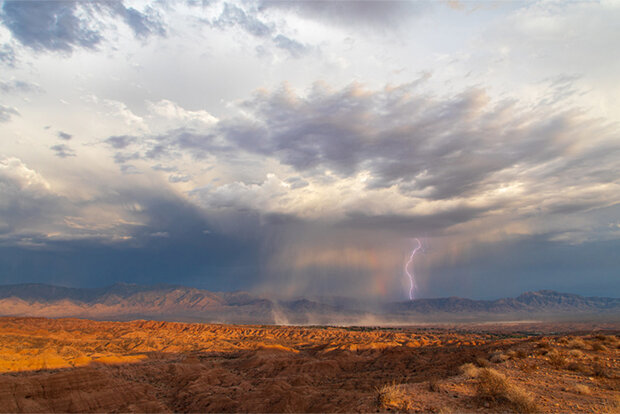 A lightning bolt emerges from a thunderstorm over the desert